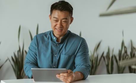 Man holds his tablet and touches the screen to engage with his online Kaplan training course
